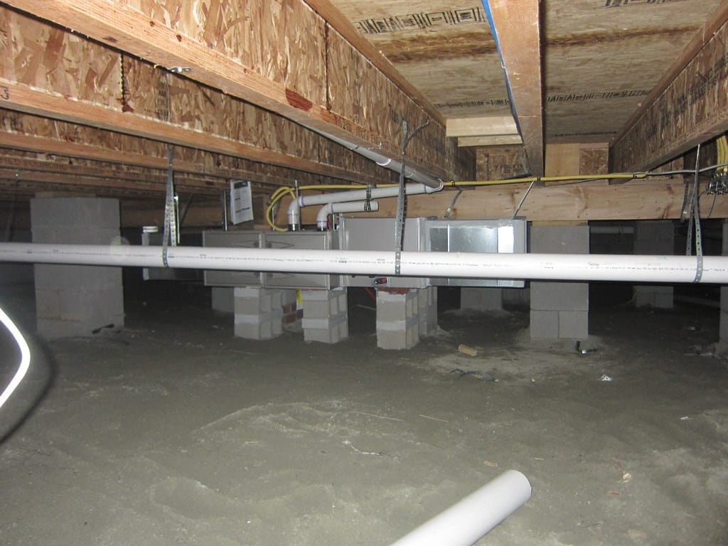 A Wilmington-area crawl space of the type we encapsulate — block piers, floor joists, and a dirt floor