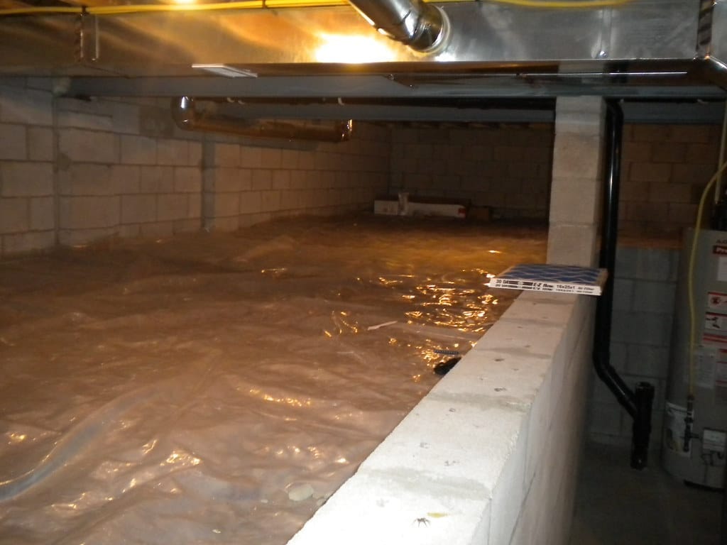 A crawl space floor covered with a plastic vapor barrier in a Wilmington-area home